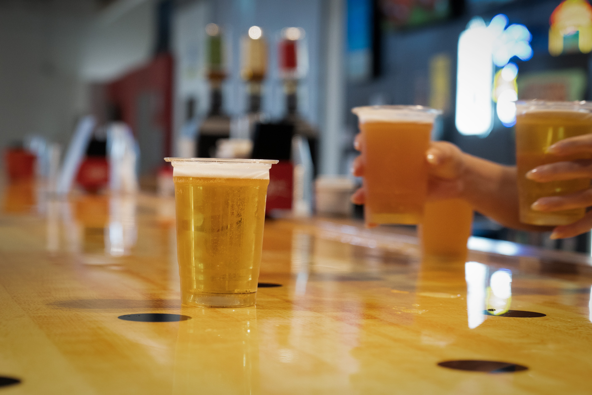 Bartender's hands holding two beers passing them over the bar